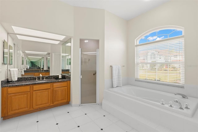 bathroom featuring plus walk in shower, vanity, a skylight, and tile patterned floors