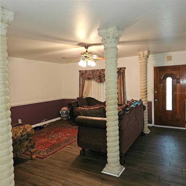 living room with decorative columns, ceiling fan, and dark wood-type flooring