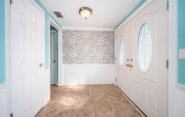 tiled foyer entrance featuring crown molding