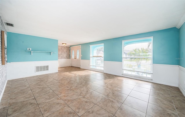 unfurnished living room with brick wall and light tile patterned flooring