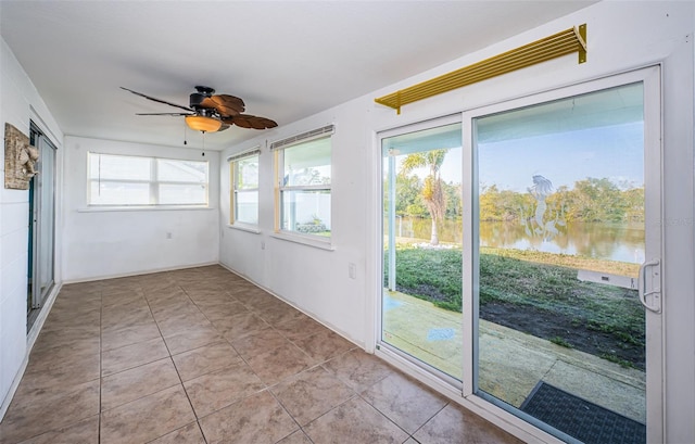 unfurnished sunroom featuring a water view and ceiling fan