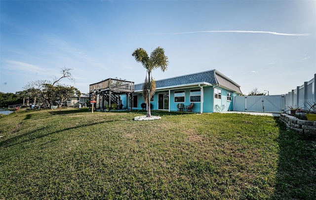 rear view of house featuring a wooden deck and a yard