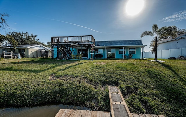 back of property with a deck and a lawn