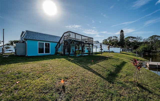 back of house featuring a deck with water view and a yard