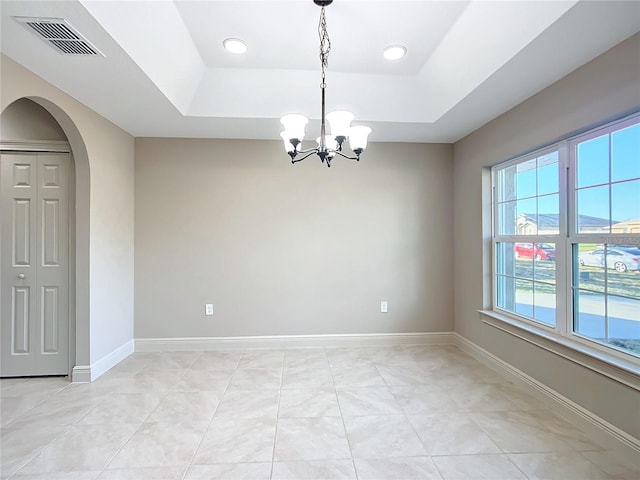 spare room featuring a chandelier, a healthy amount of sunlight, and a tray ceiling