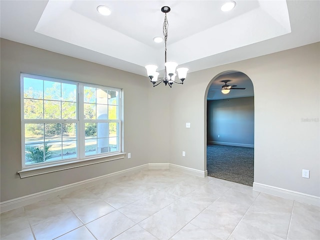 unfurnished room with ceiling fan with notable chandelier, a raised ceiling, and light colored carpet