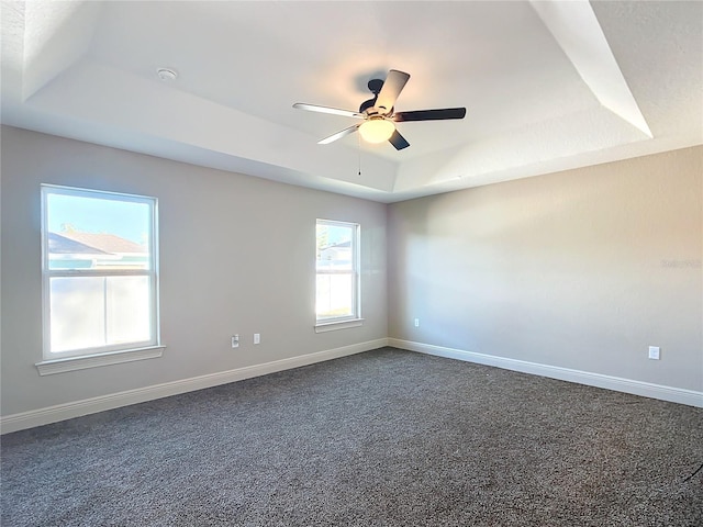 spare room with dark carpet, a raised ceiling, and ceiling fan