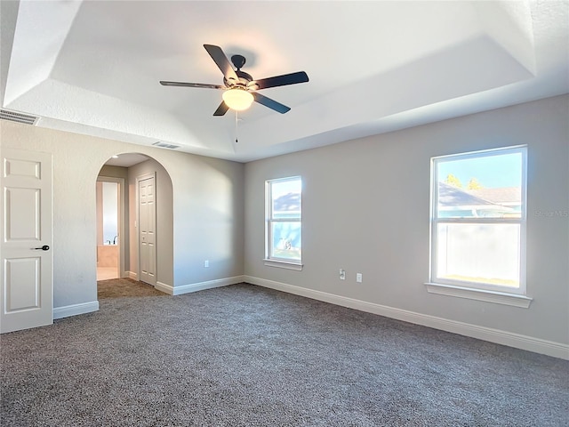 unfurnished room with carpet flooring, a tray ceiling, and ceiling fan