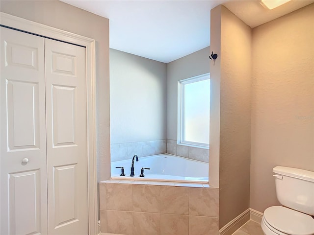 bathroom with tile patterned flooring, toilet, and tiled tub