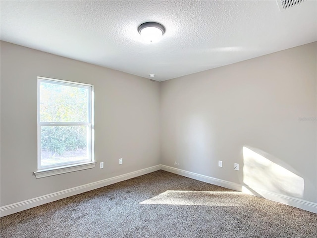 carpeted empty room featuring a textured ceiling