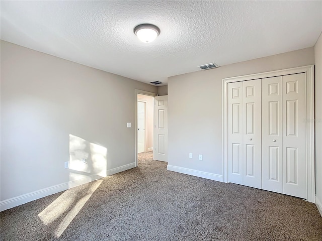 unfurnished bedroom with carpet, a textured ceiling, and a closet