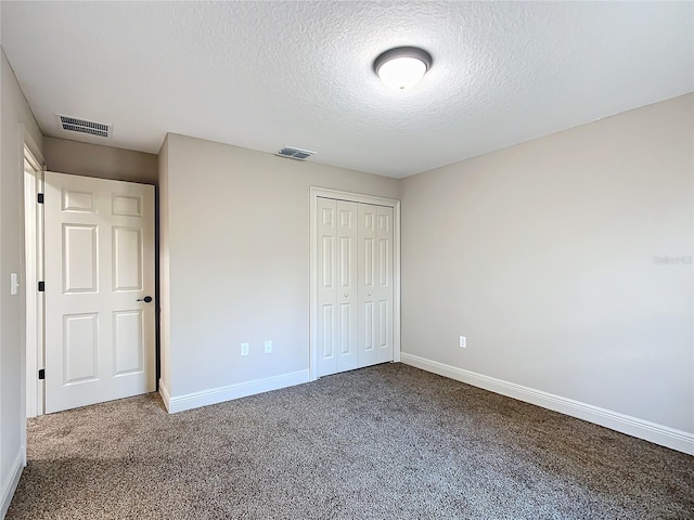 unfurnished bedroom featuring a textured ceiling, carpet floors, and a closet