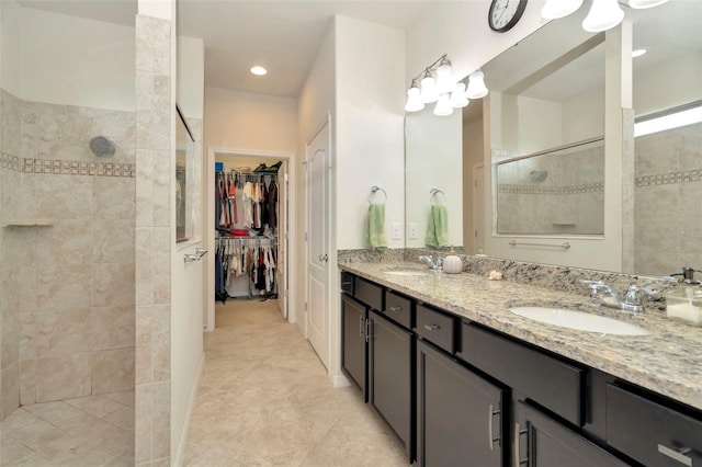 bathroom featuring tile patterned flooring, vanity, and tiled shower