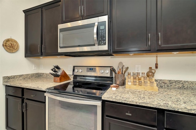 kitchen featuring dark brown cabinets, light stone countertops, and stainless steel appliances