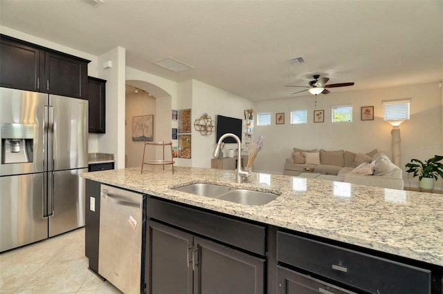 kitchen featuring light stone counters, stainless steel appliances, ceiling fan, sink, and light tile patterned floors