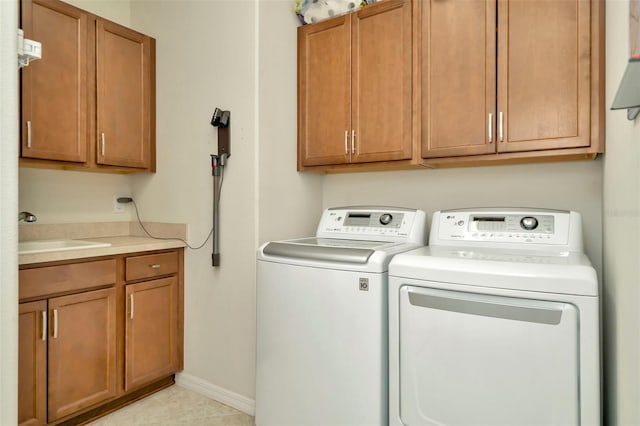 clothes washing area featuring washer and clothes dryer, light tile patterned flooring, cabinets, and sink