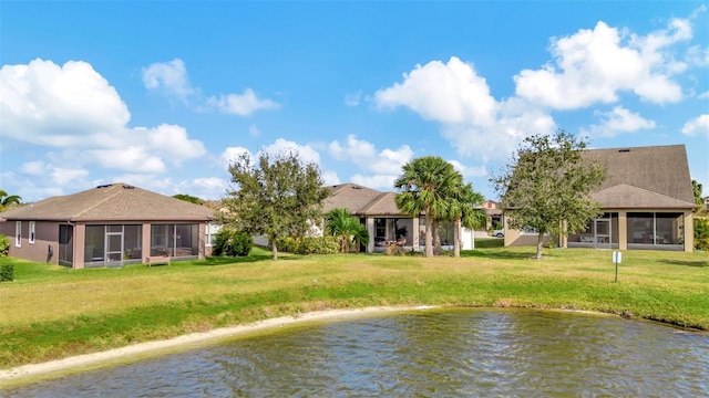 rear view of property featuring a sunroom, a yard, and a water view