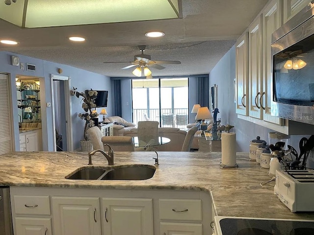 kitchen with white cabinetry, sink, ceiling fan, and a textured ceiling