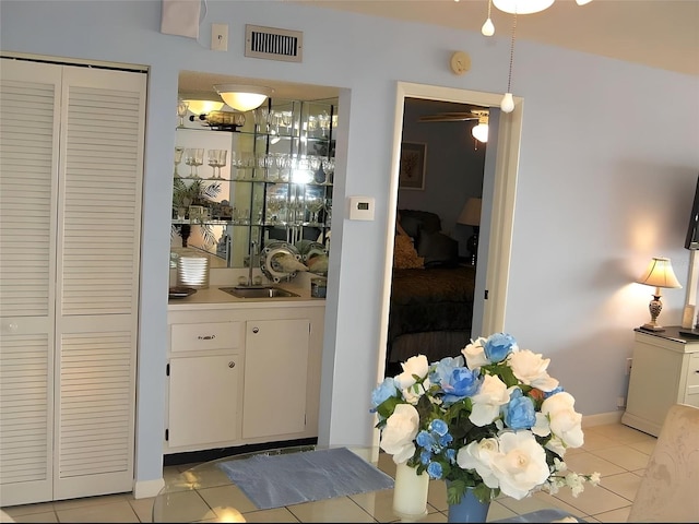 bar featuring sink, ceiling fan, light tile patterned floors, decorative light fixtures, and white cabinetry