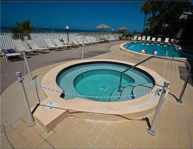 view of pool with a water view and a community hot tub