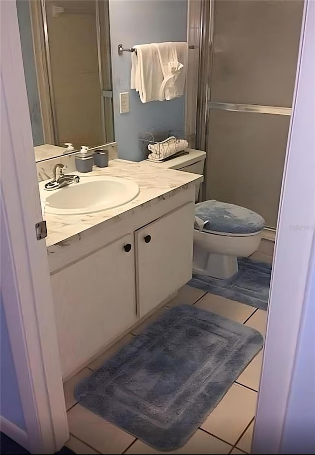 bathroom featuring tile patterned flooring, vanity, a shower with shower door, and toilet