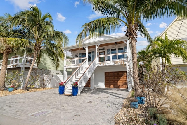 raised beach house with ceiling fan, a porch, and a garage