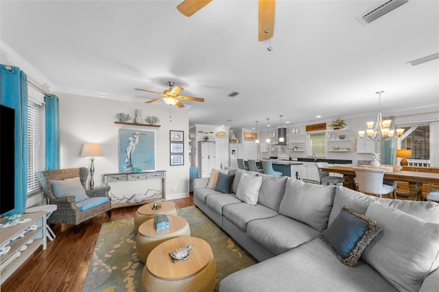 living room featuring dark hardwood / wood-style floors, ornamental molding, and ceiling fan with notable chandelier