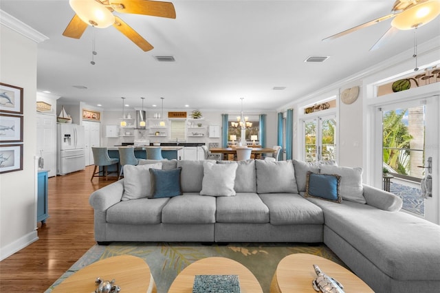 living room featuring crown molding, sink, dark wood-type flooring, and a notable chandelier