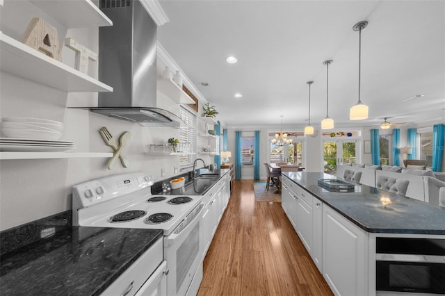 kitchen with hanging light fixtures, wall chimney exhaust hood, ornamental molding, white electric range oven, and white cabinetry