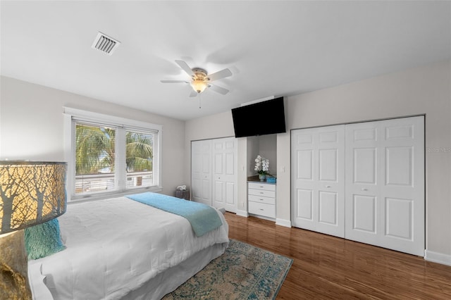 bedroom featuring ceiling fan, dark wood-type flooring, and two closets