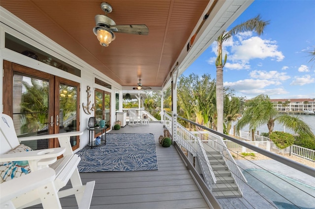 wooden deck with french doors, a water view, and ceiling fan