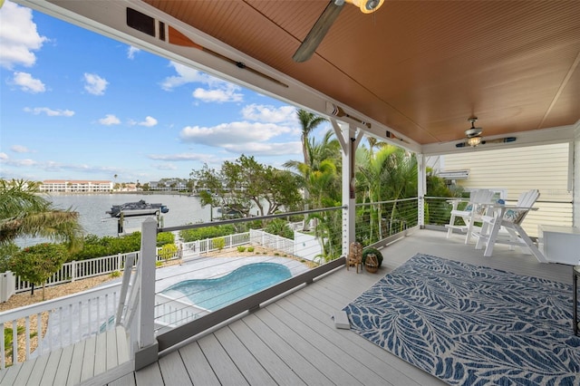 wooden terrace featuring ceiling fan, a water view, and a fenced in pool