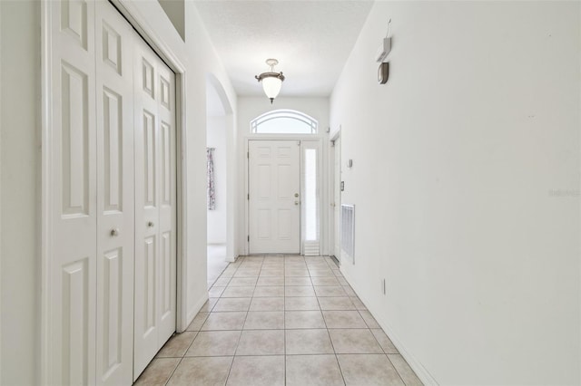 doorway to outside featuring light tile patterned flooring and a textured ceiling