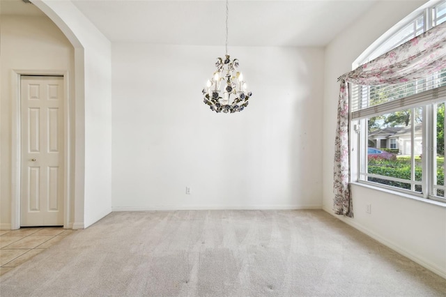 empty room with light colored carpet and an inviting chandelier