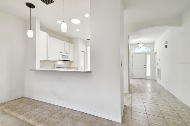 kitchen with kitchen peninsula, white cabinetry, light tile patterned floors, and white appliances