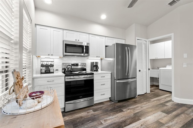 kitchen with appliances with stainless steel finishes, washer / clothes dryer, white cabinetry, and dark hardwood / wood-style floors