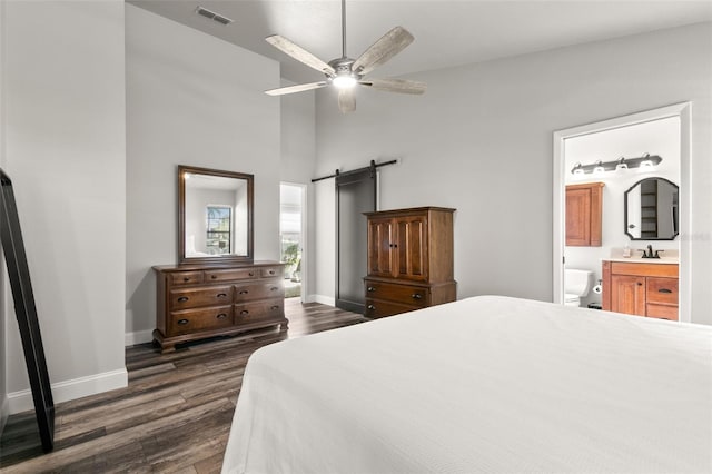 bedroom with sink, ensuite bath, ceiling fan, a barn door, and dark hardwood / wood-style flooring