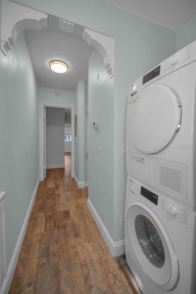 washroom featuring ornamental molding, stacked washer and clothes dryer, and dark hardwood / wood-style floors