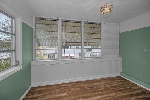 spare room with a textured ceiling, dark hardwood / wood-style floors, and a healthy amount of sunlight