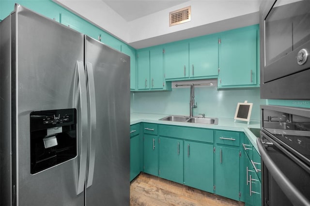 kitchen featuring stainless steel appliances, sink, light hardwood / wood-style floors, and green cabinetry