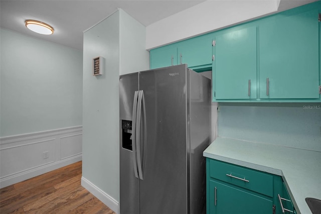 kitchen featuring hardwood / wood-style floors, green cabinets, and stainless steel refrigerator with ice dispenser