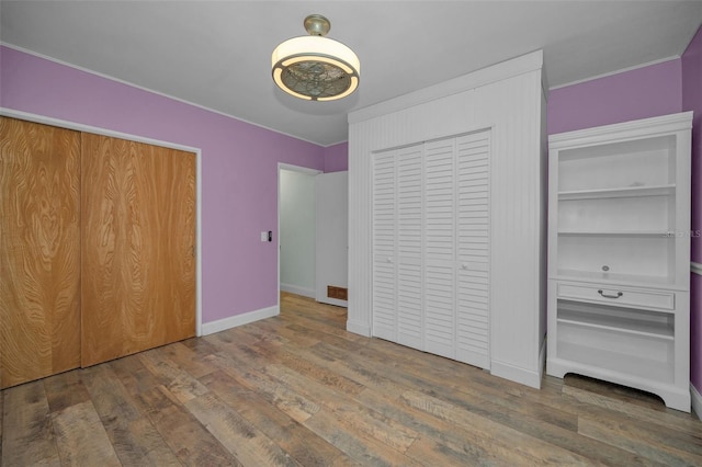 unfurnished bedroom with hardwood / wood-style floors and multiple closets