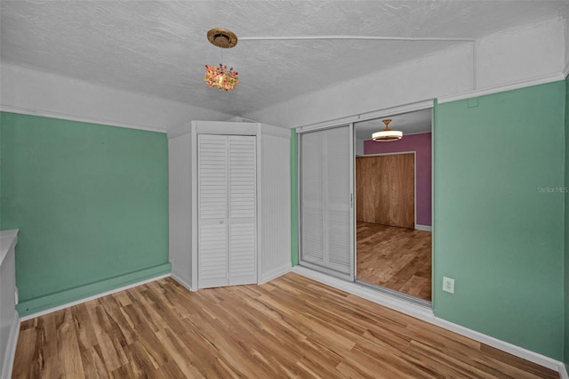 unfurnished bedroom with wood-type flooring, a closet, and a textured ceiling