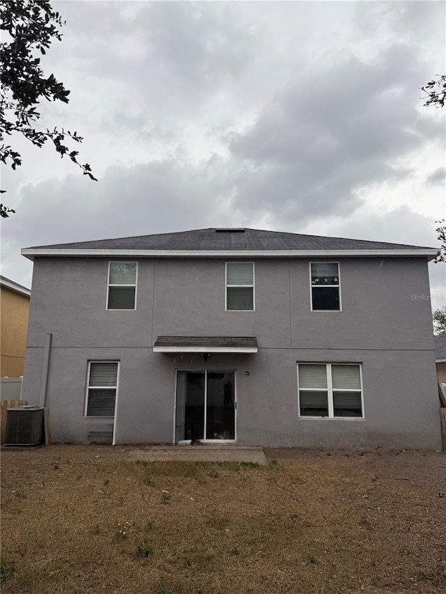 rear view of house featuring a lawn and central air condition unit