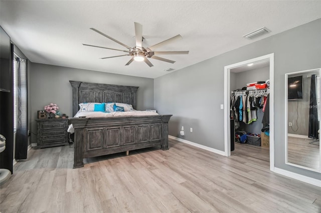 bedroom with ceiling fan, a walk in closet, light hardwood / wood-style flooring, and a closet