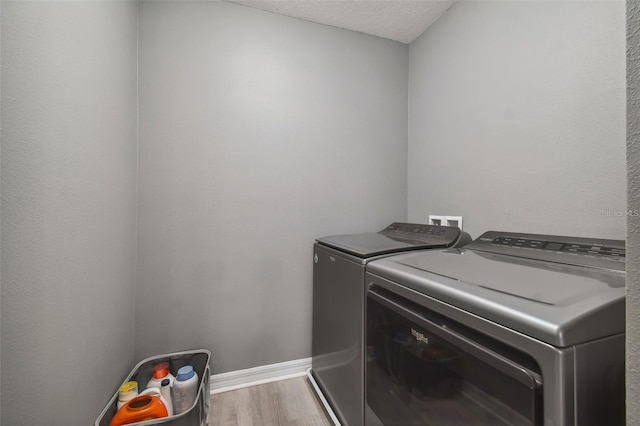 laundry area with washing machine and clothes dryer, light hardwood / wood-style flooring, and a textured ceiling