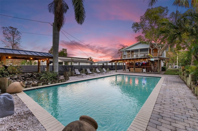 pool at dusk featuring a gazebo, a patio area, and pool water feature