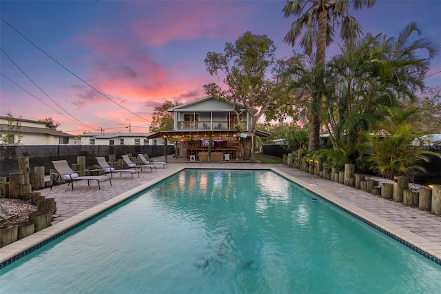 pool at dusk featuring a patio area