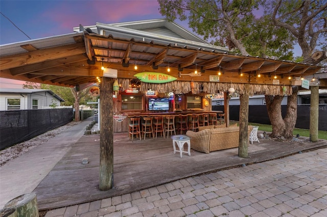 patio terrace at dusk with exterior bar and a deck