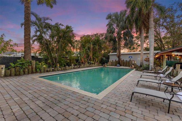 pool at dusk featuring a patio